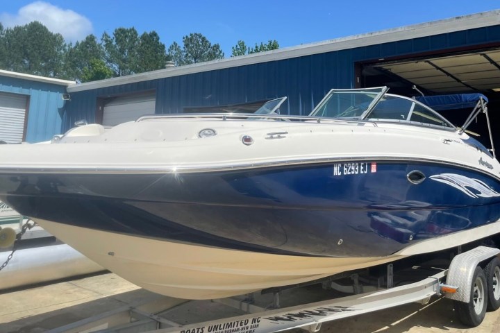 Blue and white speedboat on a trailer outside a blue building.