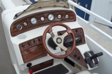 Boat cockpit with steering wheel, gauges, and control panel.